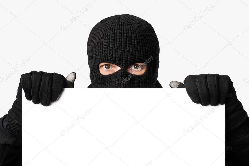Masked thief peeking out white blank board