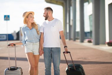 Mutlu çift havaalanında bavullarıyla yürüyor.