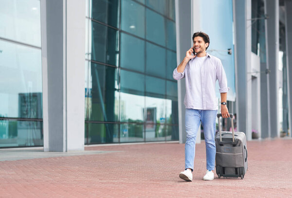 Calling taxi. Millennial man arriving at airport, ordering car by cellphone