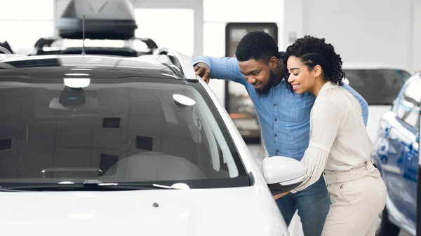 Пара вибирає автомобіль разом, що стоїть біля машини в шоловій кімнаті (панорама). — стокове фото