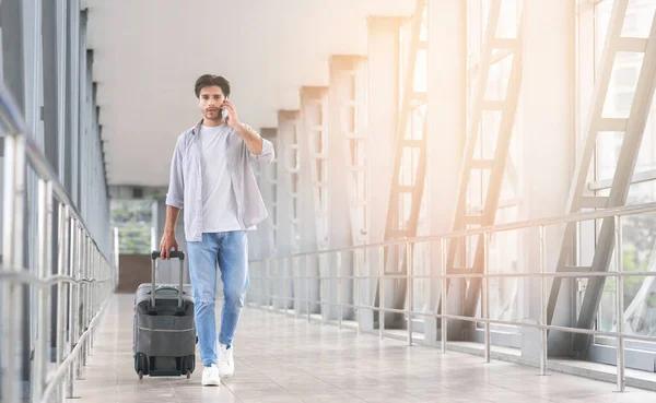 Millennial Man camminando con i bagagli in aeroporto e parlando sul cellulare — Foto Stock