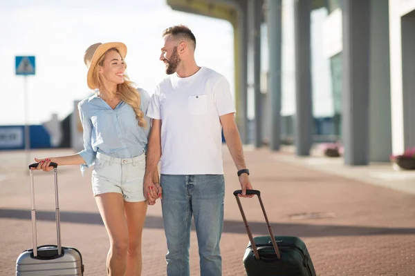 Coppia felice che cammina in aeroporto con bagaglio — Foto Stock