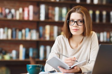 Hayalperest genç gazeteci deftere makale yazma fikirleri yazıyor.