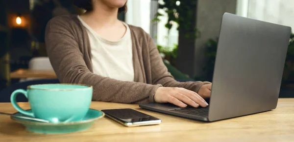 Ugjenkjennelig kvinne som sitter på internettkafeen med laptop – stockfoto