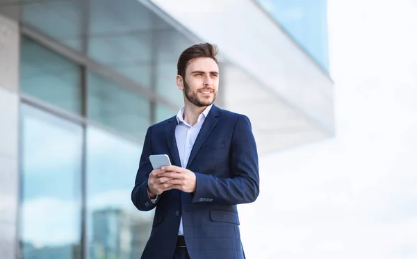 Financiero guapo en traje de negocios navegar por la web en su teléfono inteligente al aire libre — Foto de Stock