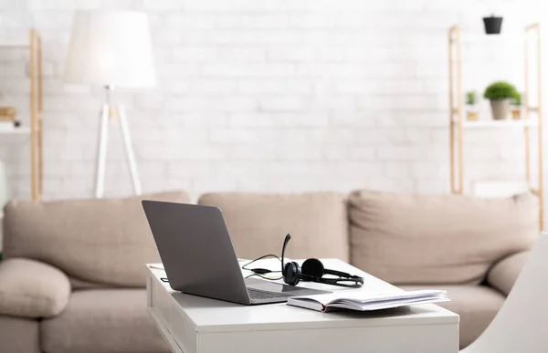 Modern freelancer workplace at home. Desk with laptop, headphones and notepad