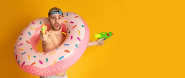 Guy in inflatable ring shoots water guns — Stock Photo, Image