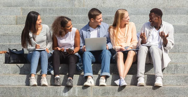 Multiracionális vidám diákok beszélgetnek, miközben együtt tanulnak a parkban — Stock Fotó