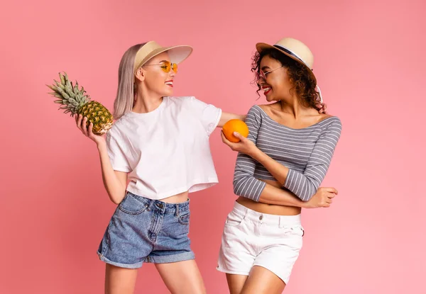 Dieta de Verão. Duas meninas alegres em roupas elegantes segurando frutas tropicais — Fotografia de Stock