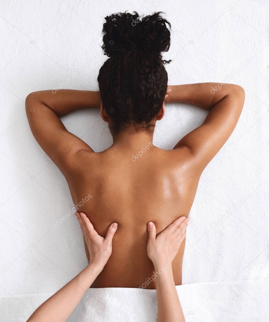 Unrecognizable african woman having back massage, white background
