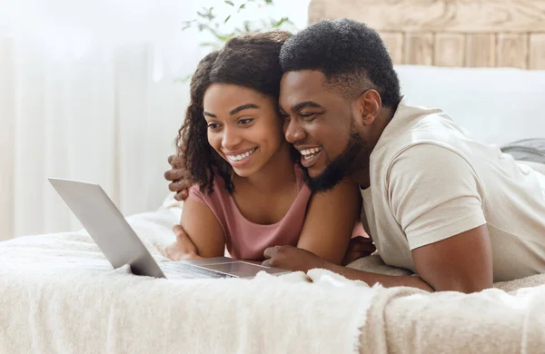 Schwarzes verliebtes Paar surft zusammen im Internet und liegt auf dem Bett — Stockfoto