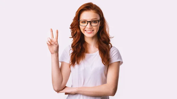 Positive rothaarige Mädchen gestikulieren Victory V-Zeichen auf weißem Hintergrund, Panorama — Stockfoto