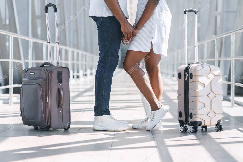 Happy Reunion. Loving black couple holding hands at airport terminal, cropped