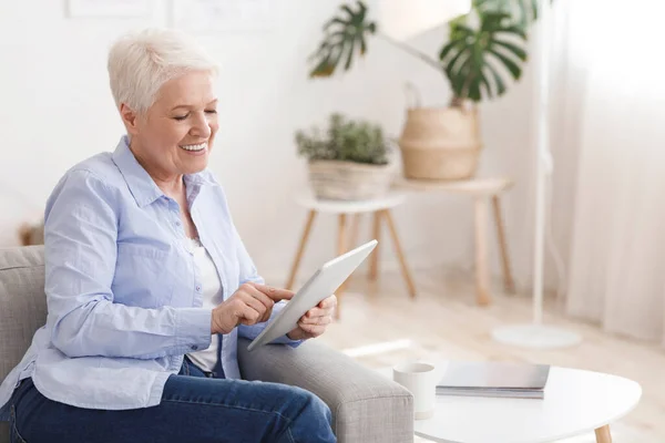 Moderní klid. Veselý starší dáma pomocí digitální tablet doma — Stock fotografie