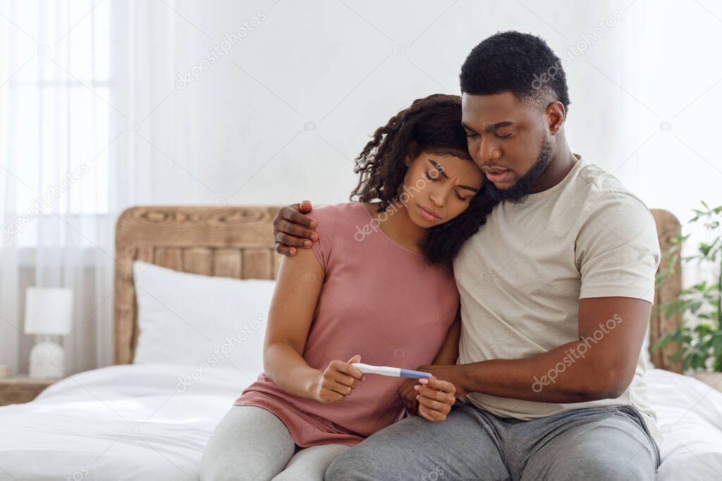 Upset black couple with a negative pregnancy test result