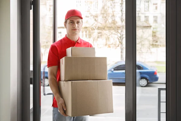 Compras online sem sair de casa e entrega rápida. Correio em uniforme detém caixas de papelão — Fotografia de Stock