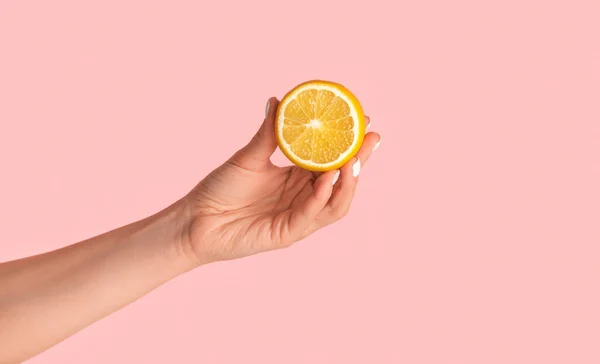 Vista close-up da menina milenar mostrando frutas de laranja cortadas no fundo rosa — Fotografia de Stock