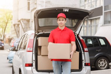 Kurye müşteriye gider, paketi eve teslim eder. Teslimatçı bagajın yanında.