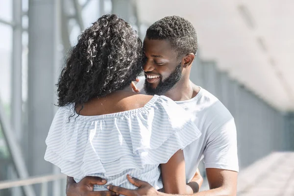 Romance a la llegada. Pareja negra abrazándose tiernamente en el corredor del aeropuerto — Foto de Stock