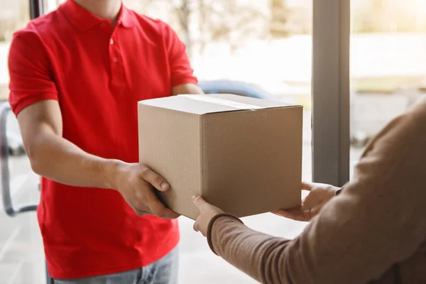 Erhalten Sie eine Bestellung, ohne das Haus zu verlassen. Kurier übergibt Paket an Mädchen — Stockfoto