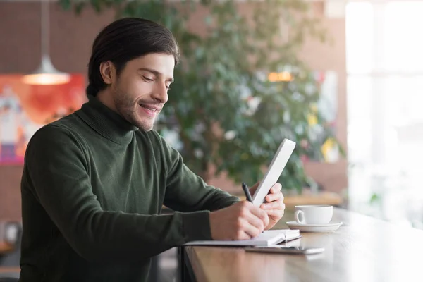 Zakenman die 's ochtends koffie drinkt in café, zijn dag aan het plannen — Stockfoto