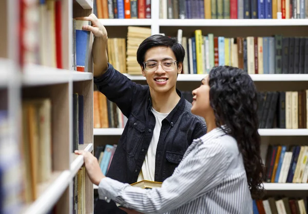 Happy japanese guy taking book at library for his girl — Stock Photo, Image