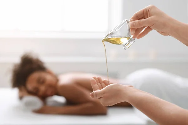Terapeutka aplikující masážní olej na ruce před terapií — Stock fotografie