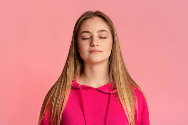 Chica adolescente con los ojos cerrados disfrutar del momento, aislado sobre fondo rosa — Foto de Stock
