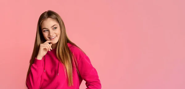 Coqueteando chica adolescente sonriente toca su barbilla y mira a un espacio vacío —  Fotos de Stock