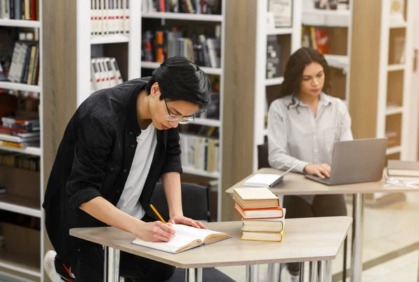 Estudante coreano tomando algumas notas na biblioteca — Fotografia de Stock