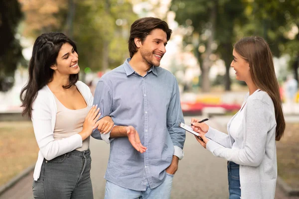 Chica entrevistando a votantes jóvenes que realizan una encuesta de pie al aire libre en la ciudad — Foto de Stock