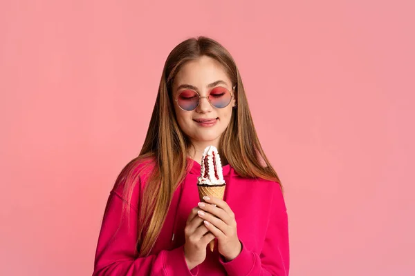 Amor por doces. Engraçado adolescente menina segura um sorvete olha para ele e lambe os lábios — Fotografia de Stock