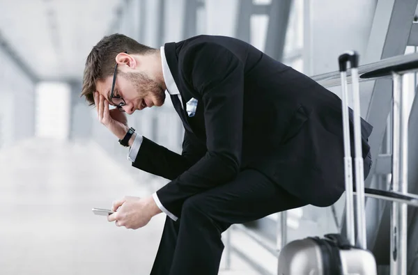 Sad urban business man texting on smart phone in airport Stock Picture