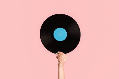 Pembe arka planda retro vinil gramofon kayıtlarını gösteren kız eli, yakın plan.