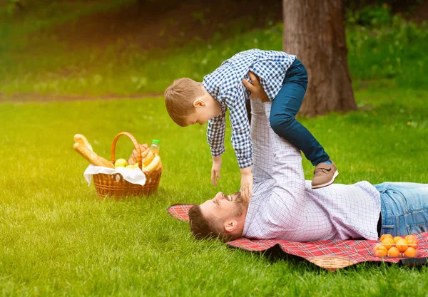 Avkopplande familje helg. Pappa leker med sin son under picknick utomhus, tomt utrymme — Stockfoto