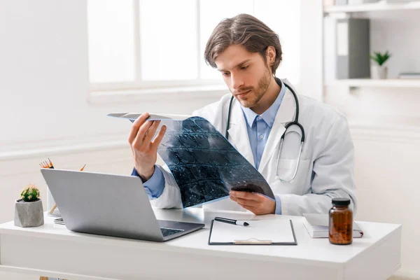 Médico serio estudiando radiografía en el consultorio —  Fotos de Stock