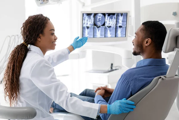 Afrikalı kadın dişçi x-ray resmi ile ekranı işaret ediyor — Stok fotoğraf