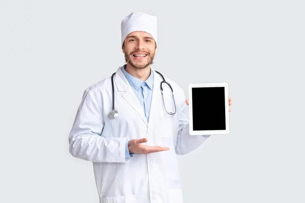 Médecin amical montrant tablette numérique avec écran blanc — Photo