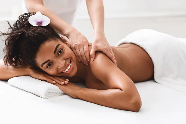 Menina africana feliz desfrutando de massagem nas costas no salão de spa — Fotografia de Stock