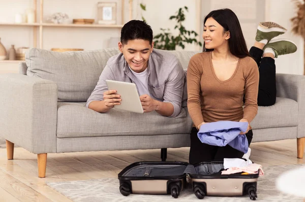 Šťastný pár pomocí tabletu počítač balení sedí s kufříkem vnitřní — Stock fotografie