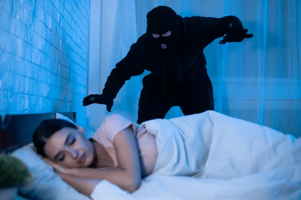 침대에서 자고 있는 여자를 공격할 태세가 된 도둑 — 스톡 사진