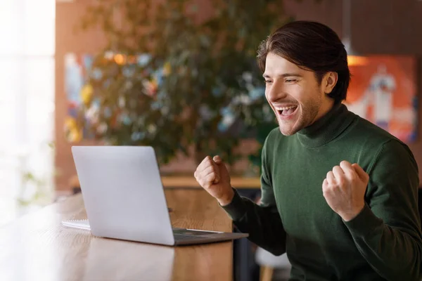 Emocjonalny facet patrząc na laptopa i krzycząc, dostał wymarzoną pracę. — Zdjęcie stockowe