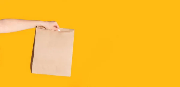 오렌지 색 배경 과빈 공간에 테이크 웨이 음식을 담은 종이봉투를 든 천년기 여성 — 스톡 사진