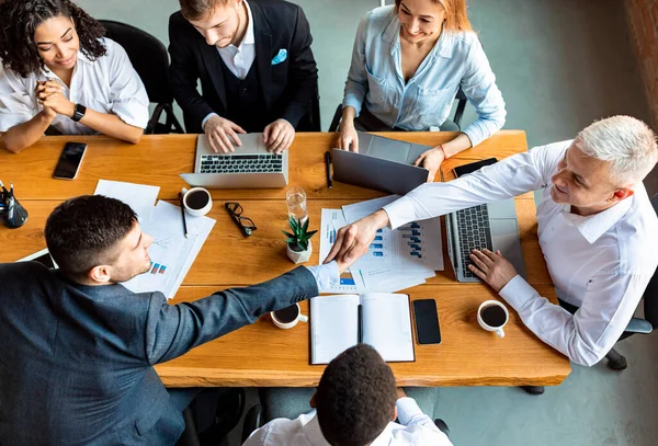 Empresarios apretones de manos durante reunión corporativa sentados en la mesa en la oficina — Foto de Stock