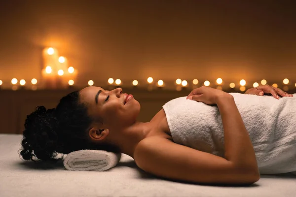 Avslappnad svart kvinna ligger på massage bord på spa — Stockfoto