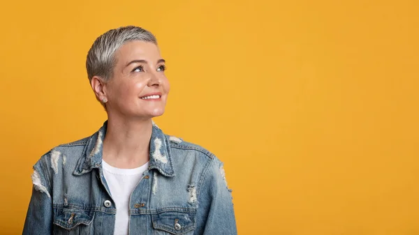 Sorrindo elegante mulher de meia-idade olhando para cima no espaço de cópia com interesse — Fotografia de Stock