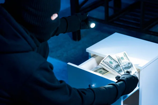손전등을 사용하여 서랍에서 돈을 훔치는 강도 — 스톡 사진