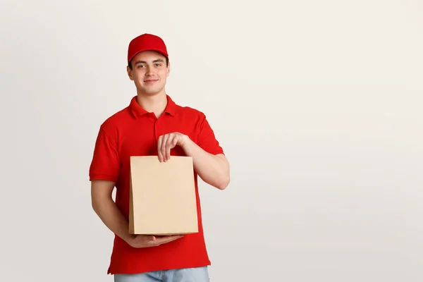 Consegna di cibo e prodotti fragili. Deliveryman tiene con attenzione sacchetto di carta — Foto Stock