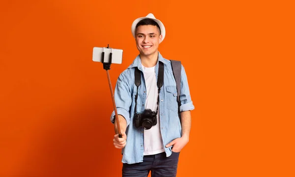 Chico positivo turista tomando selfies con smartphone y selfie stick — Foto de Stock