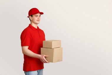 Çevrimiçi sipariş ve kurye. Kırmızı üniformalı teslimatçı elinde kutular tutuyor.